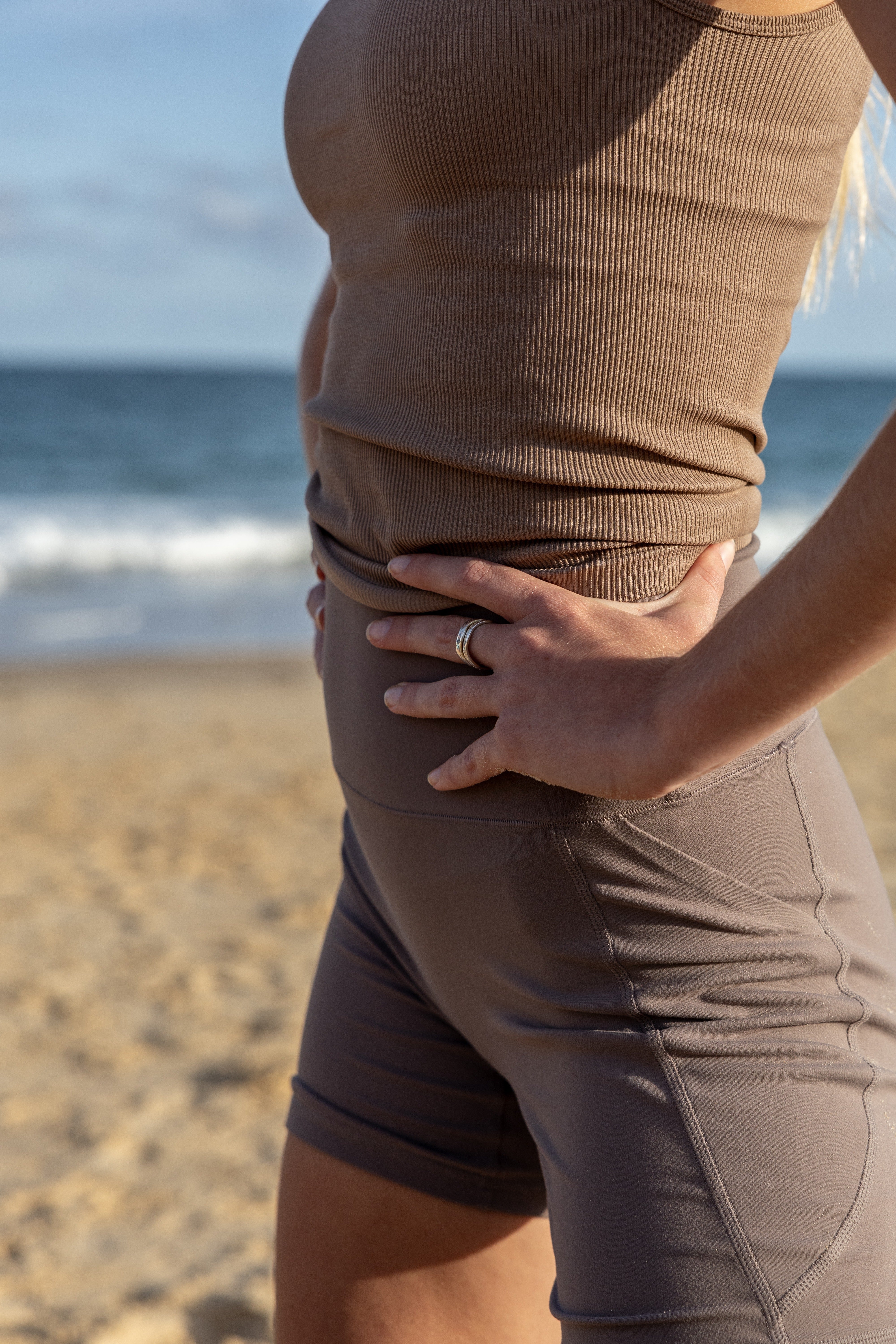 Close up of woman's torso in beige activewear at the beach