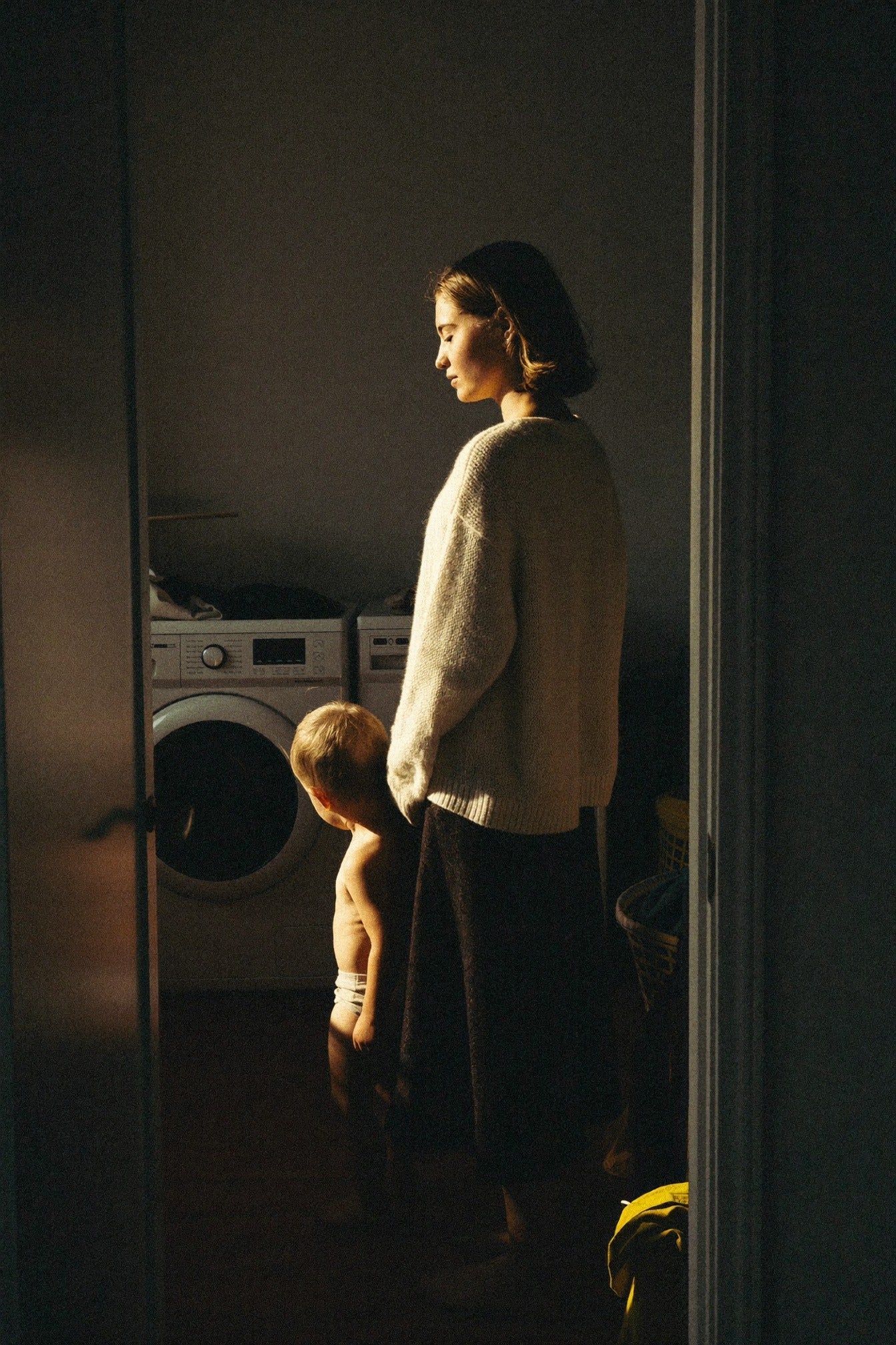 Woman and child standing in golden light in a laundry