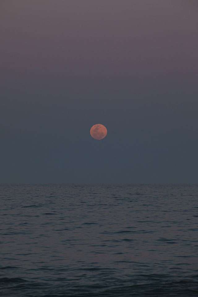 Red moon rising over the ocean