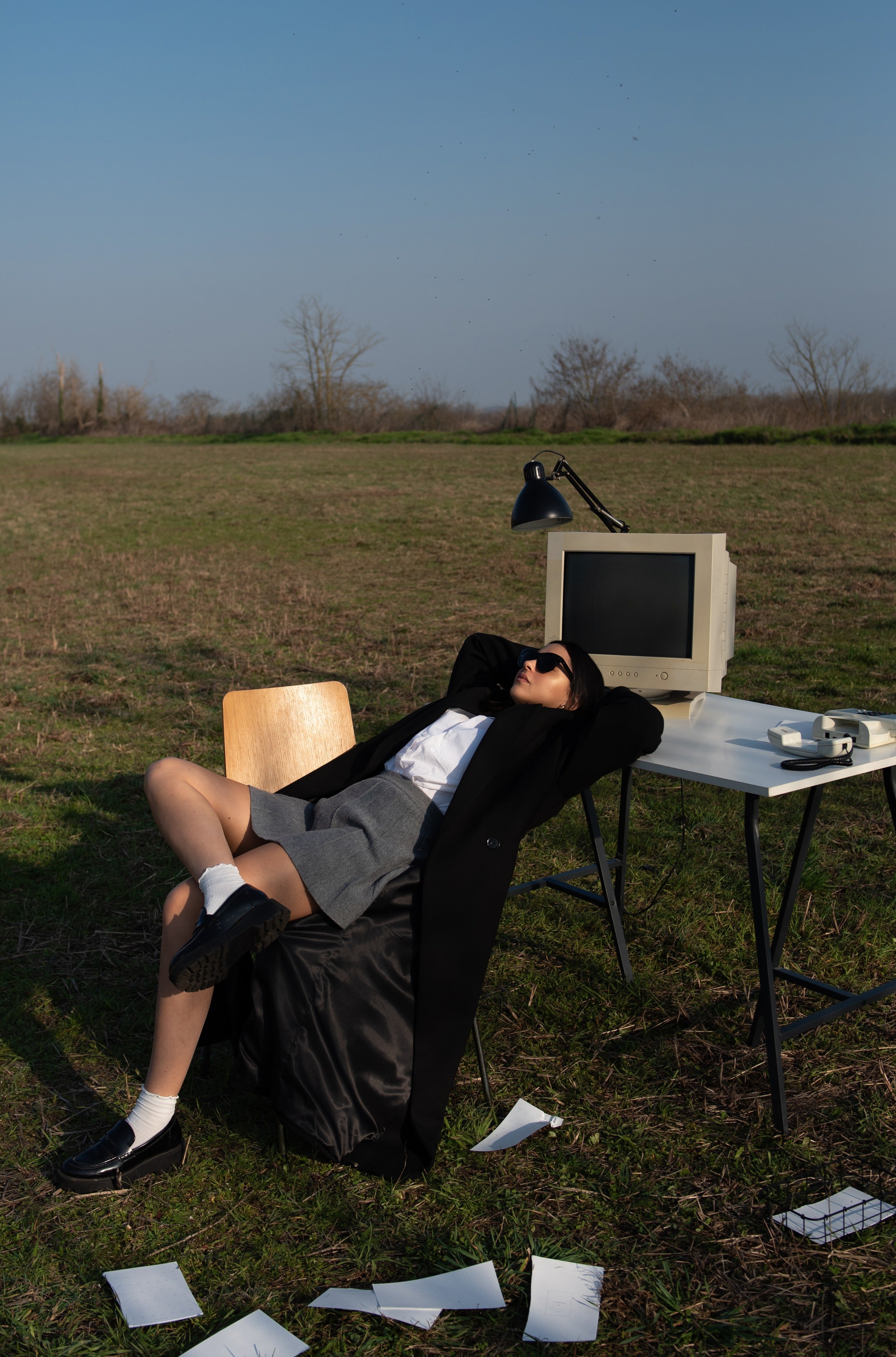 Woman in work attire kicking back in a field