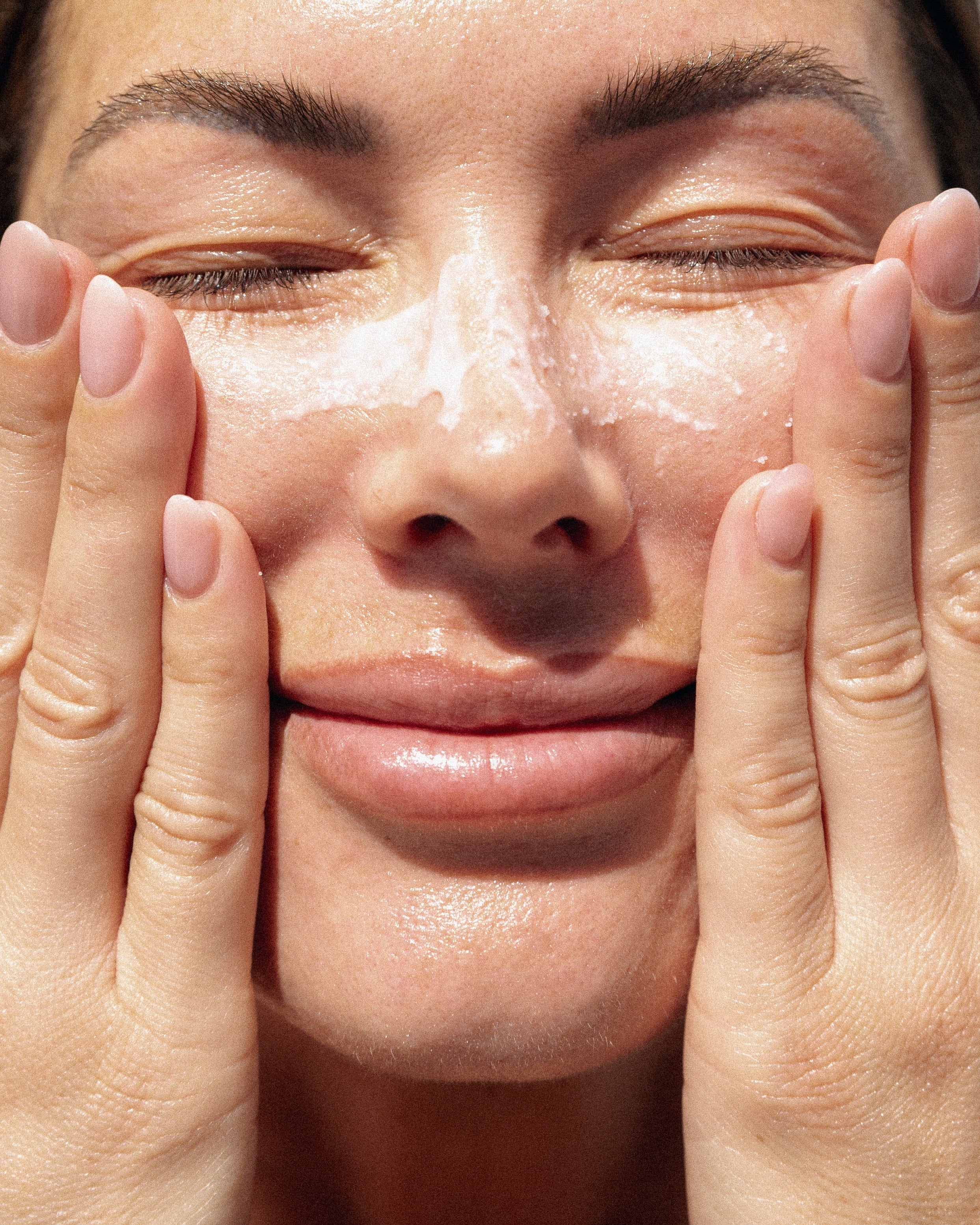 Close up of woman's face smiling and applying cream