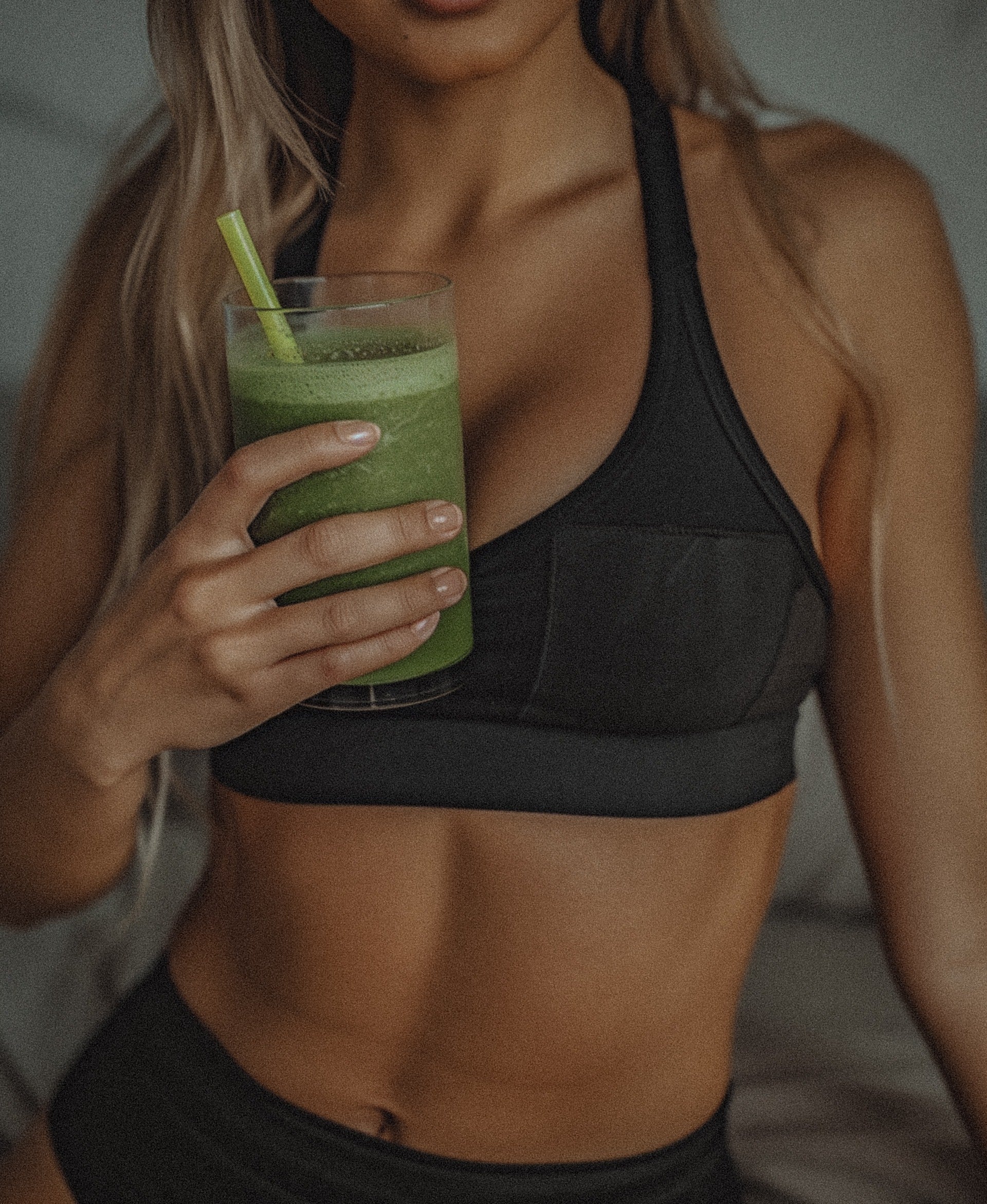 Woman holding a green smoothie wearing activewear